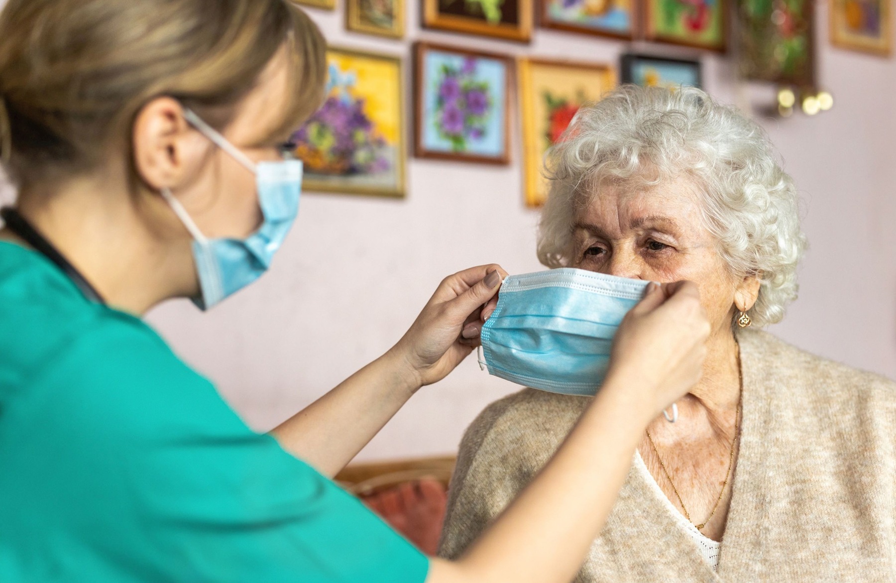Bild Pflegerin setzt Rentnerin eine Maske auf