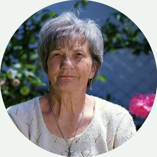 Portrait einer älteren, freundlich in die Kamera schauenden Dame im Freien 