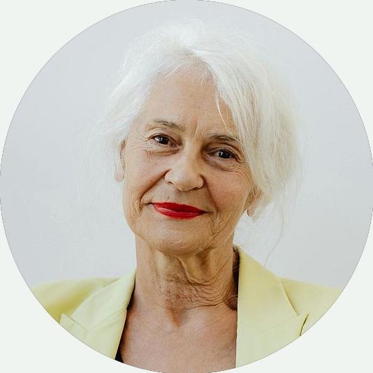 Portrait einer älteren Dame mit rotem Lippenstift lächelt freundlich in die Kamera