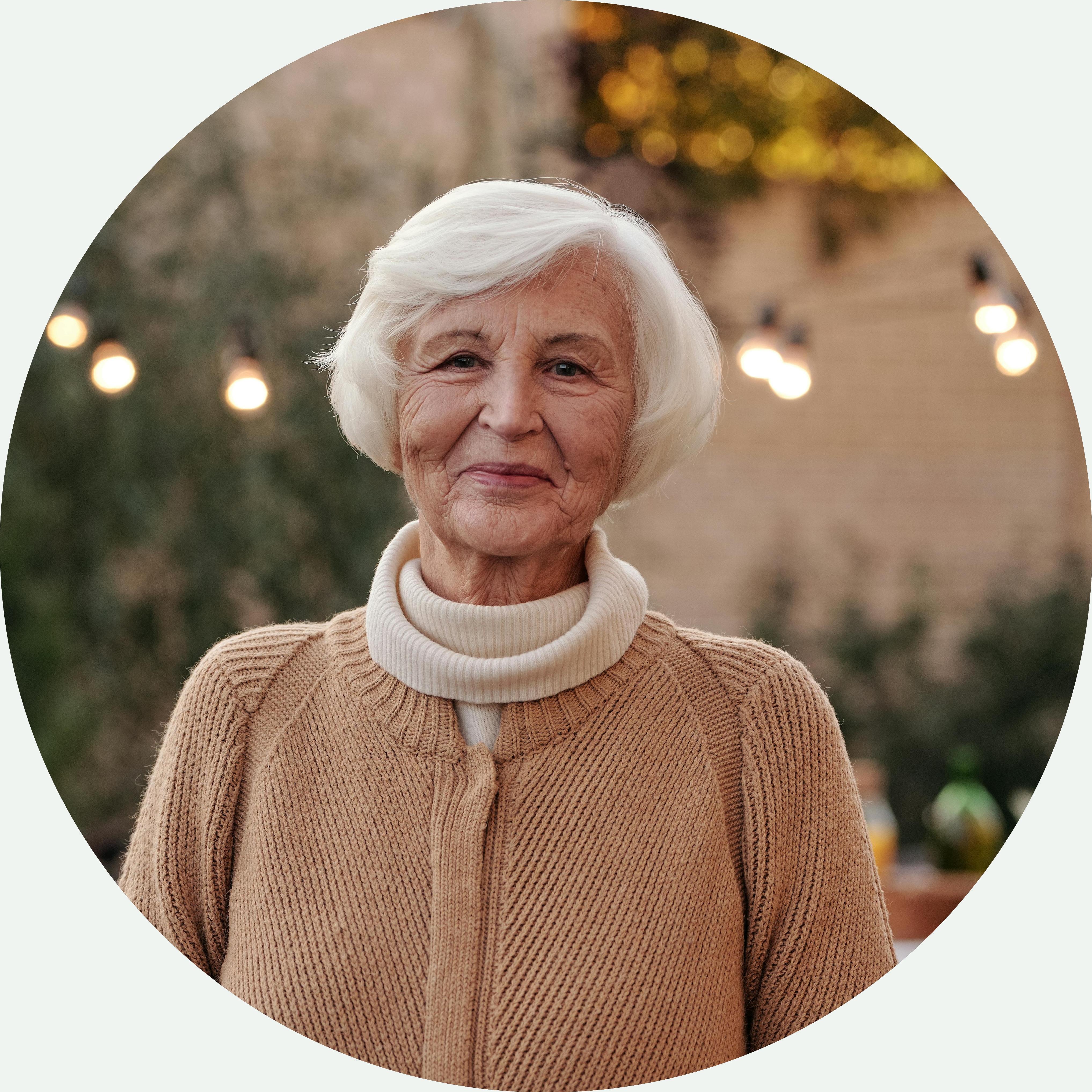 Portrait einer älteren, freundlich in die Kamera schauenden Dame im Freien