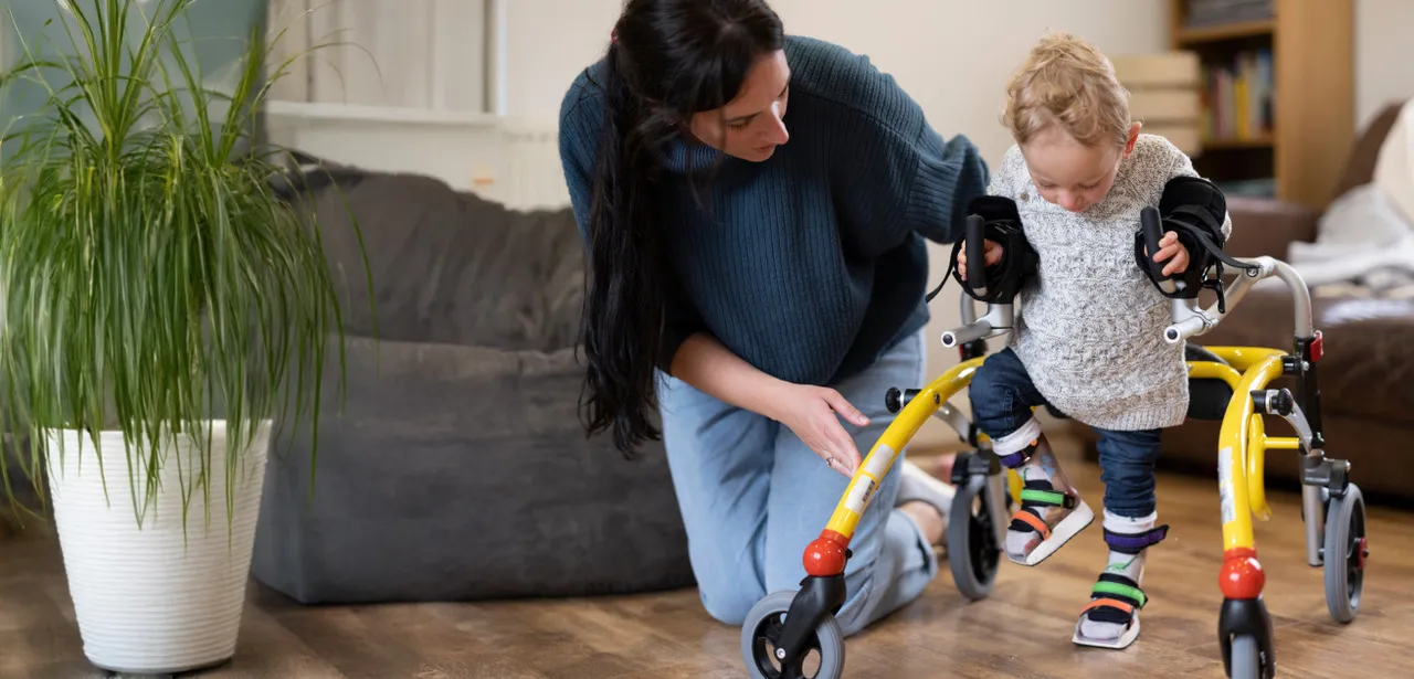 Pflegende Muttre mit Kind welches Orthesen trägt und einen Walker nutzt