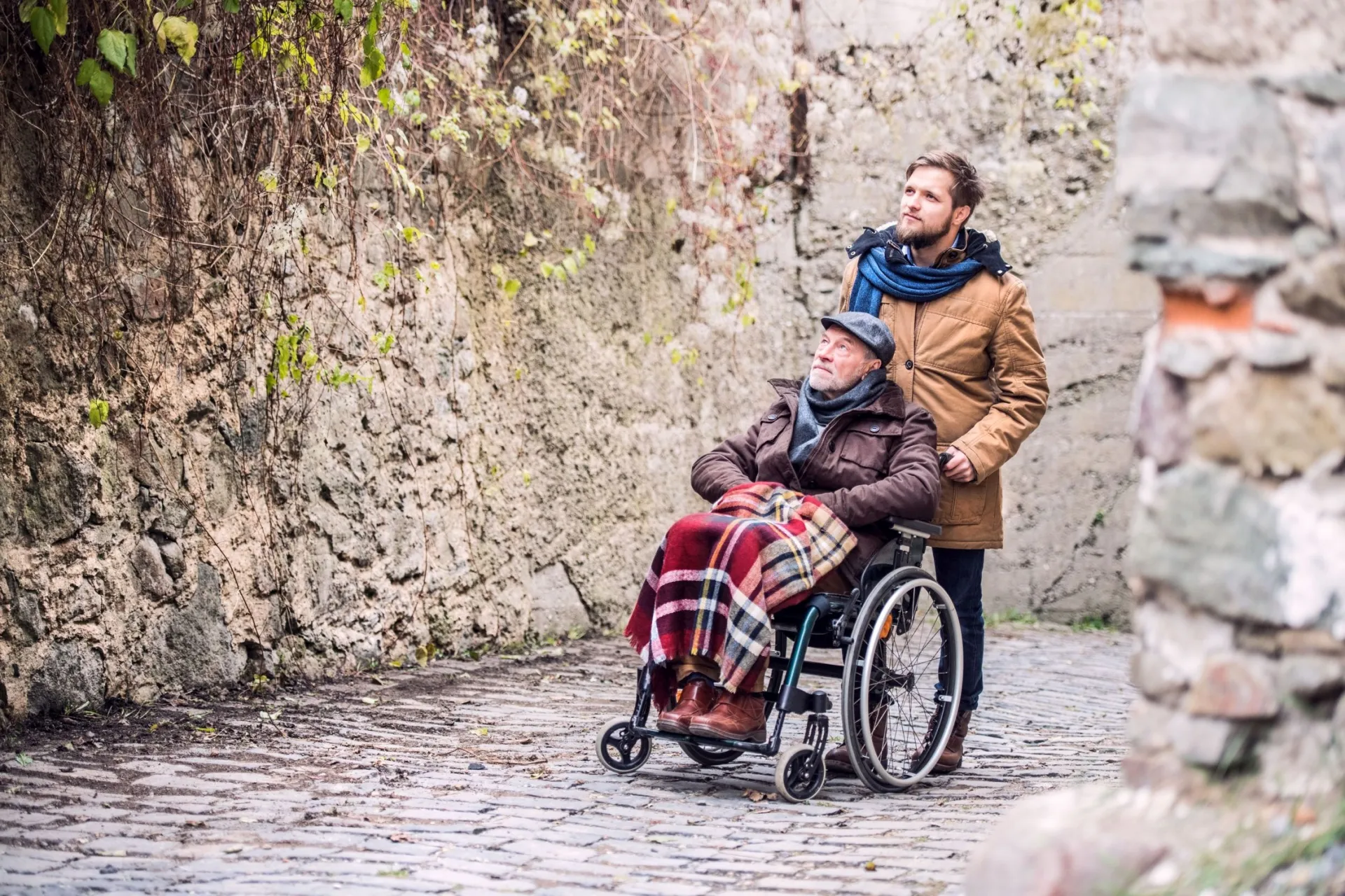 Mann schiebt Rentner im Rollstuhl