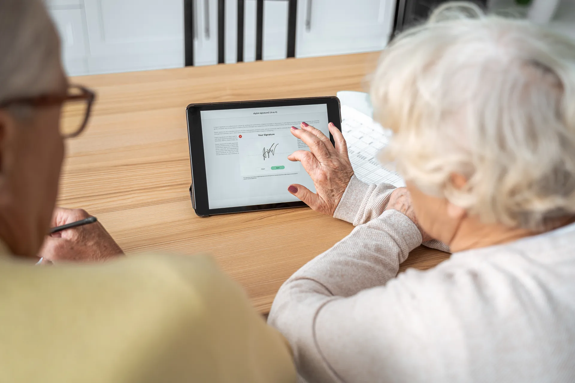 Seniorin unterschreibt auf einem Tablet