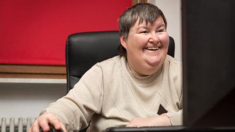Frau mit einer Behinderung bedient einen PC