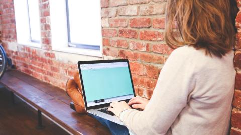 Frau sitzt an Laptop