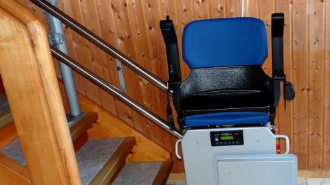 Eingebauter blauer Treppenlift am Treppenanfang einer Wohnung, ohne Person