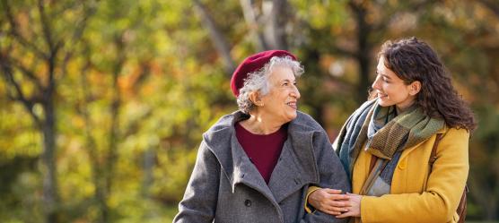 Seniorin und Schwiegertochter spazieren Arm in Arm im Park
