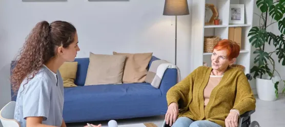 Pflegerin bespricht sich mit Frau im Rollstuhl