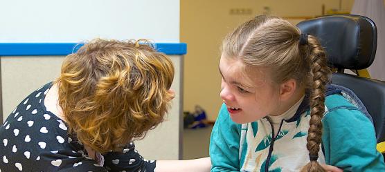 Bild einer Frau die mit einem Mädchem mit Behinderung spricht