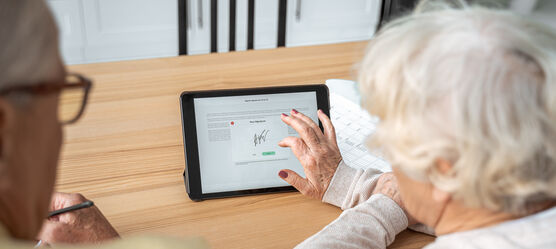 Seniorin unterschreibt auf einem Tablet