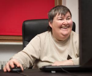Frau mit einer Behinderung bedient einen PC