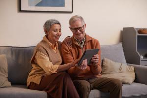 älteres Päärchen sitzt mit einem Tablet auf einem Sofa